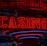 Neon lights display the word 'CASINO' in bright red, standing out against a dark background. The vibrant glow reflects a lively and bustling atmosphere.