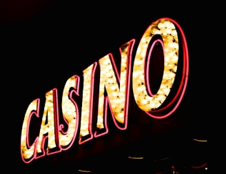 Brightly illuminated letters spell out 'CASINO' with glowing yellow bulbs and red outlines against a dark background.