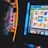 A person is closely observing a digital slot machine with colorful fruit symbols, bars, and a bell. The slot machine screen displays symbols like oranges, plums, cherries, and clouds. The background is dimly lit, creating a focused and somewhat intense atmosphere.